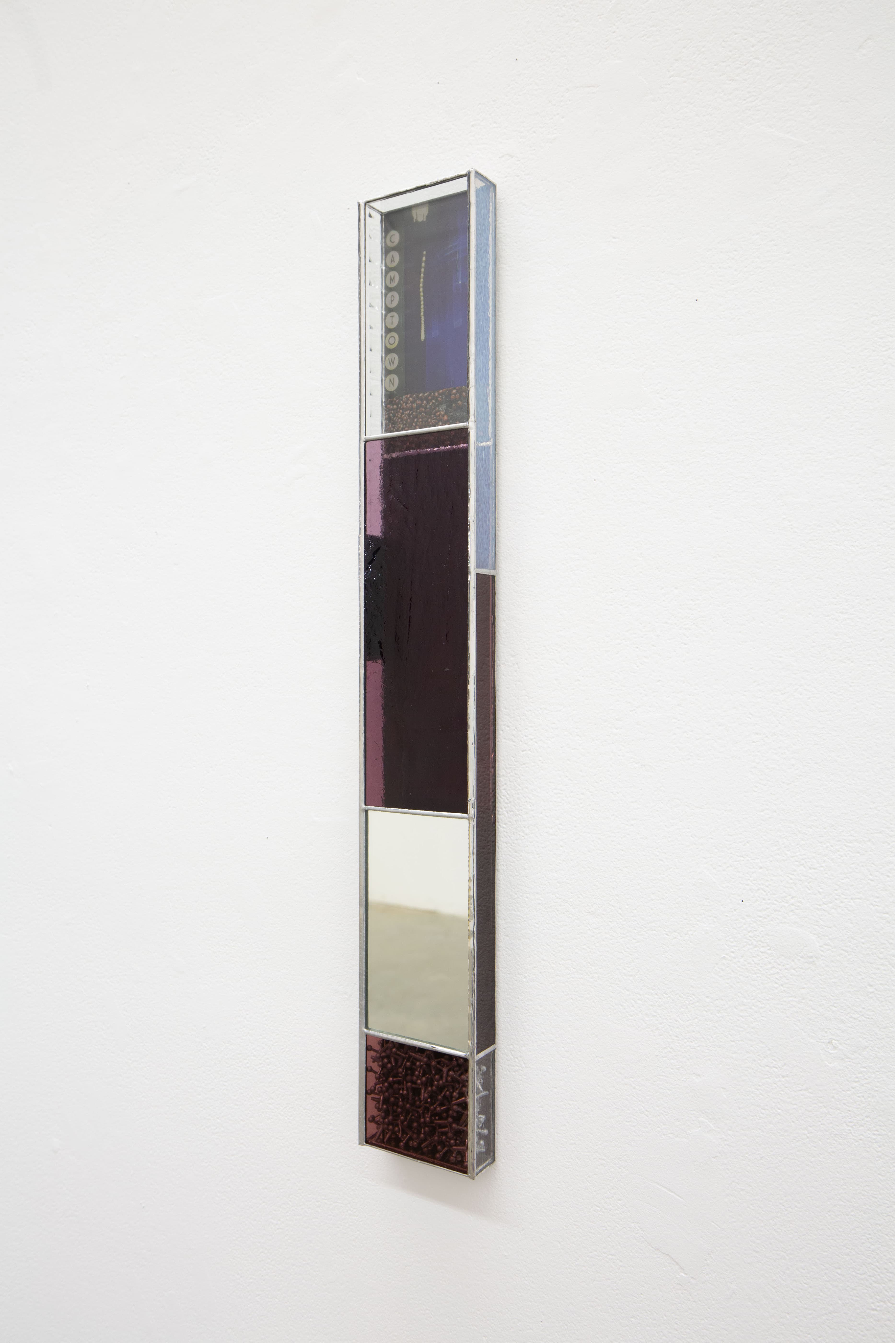 Wall hanging rectilinear stained glass and steel soldered to resemble a vertically elongated enclosed box. At the top, the transparent glass frames UV-printed images, similar to a shadowbox, collaging a grid of images; “Camptown” marquee sign, a blurry image from inside of a dark bathhouse, and winter ladybug aggregation. In between, a mirror reflecting back the viewer and/or the installation space. At the bottom are enclosed steel jacks compacted together. The stained glass varies in color and visibility; purple, red and white with semi transparent, transparent and opaque textures.
