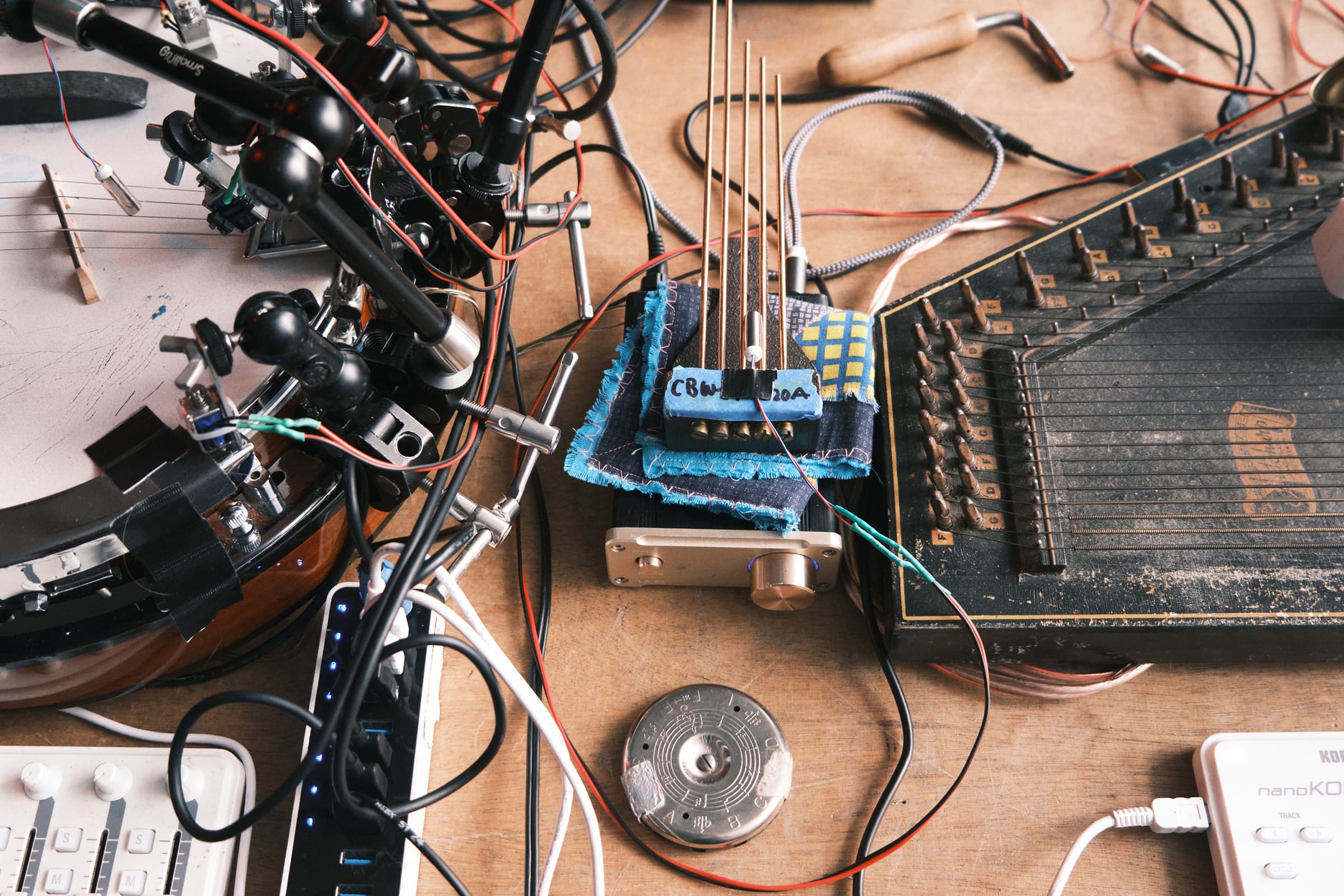 A banjo and an autoharp on a table, with various motors and devices hooked up to them.