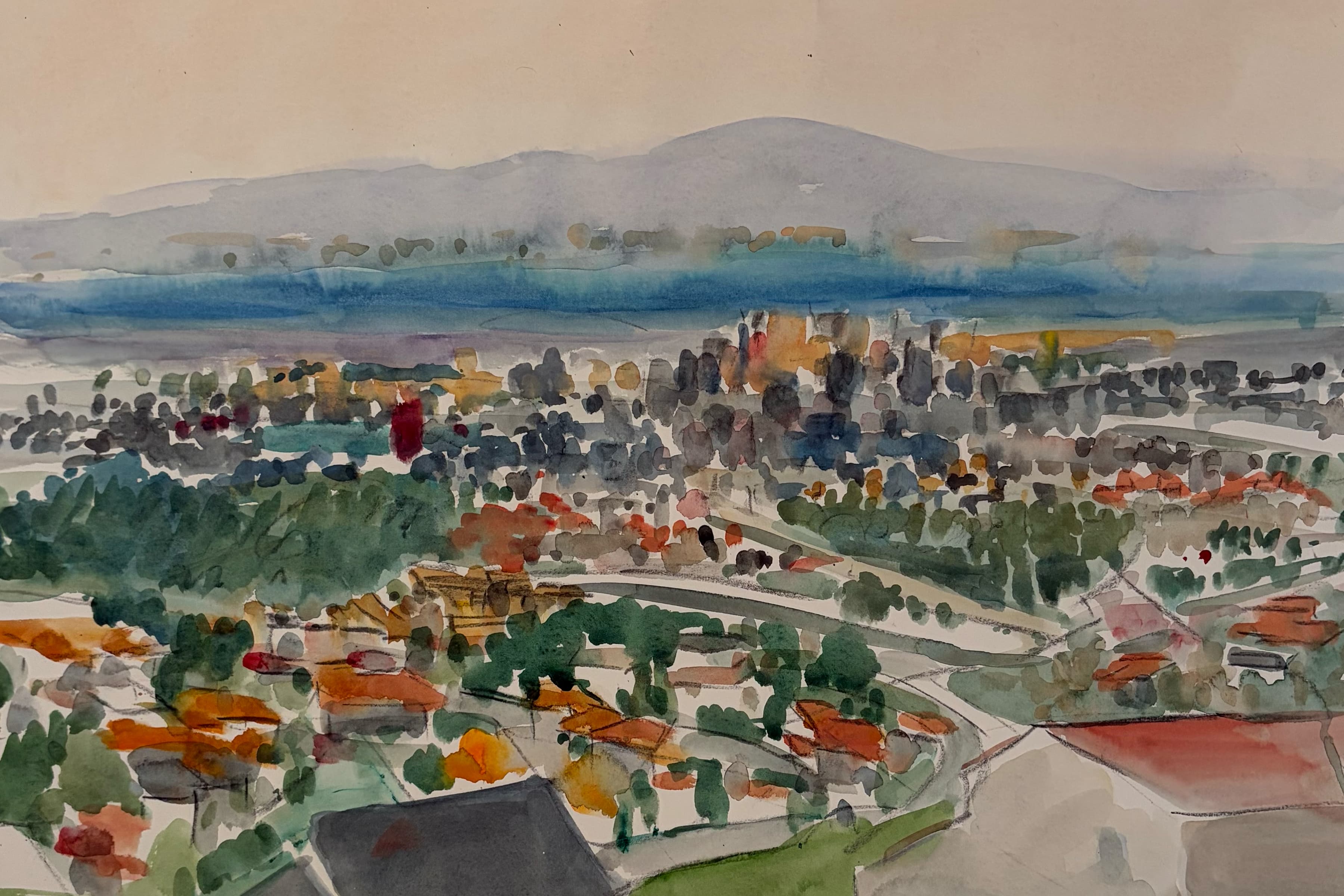 Watercolor painting depicting an elevated, impressionistic view of a town or city, nestled between green trees and a distant body of water under soft blue hills.
