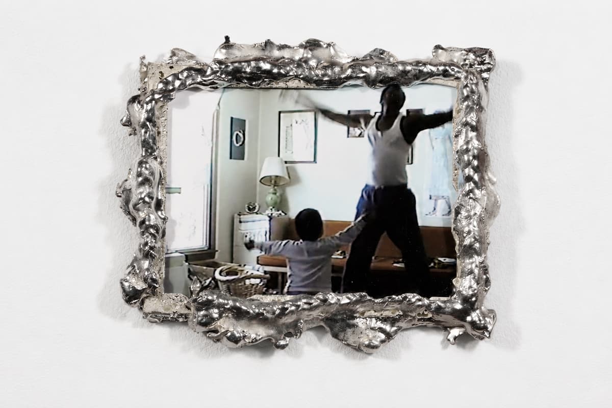 VHS still image of parent and child dancing in a living room, framed by an organic pour of shined pewter.
