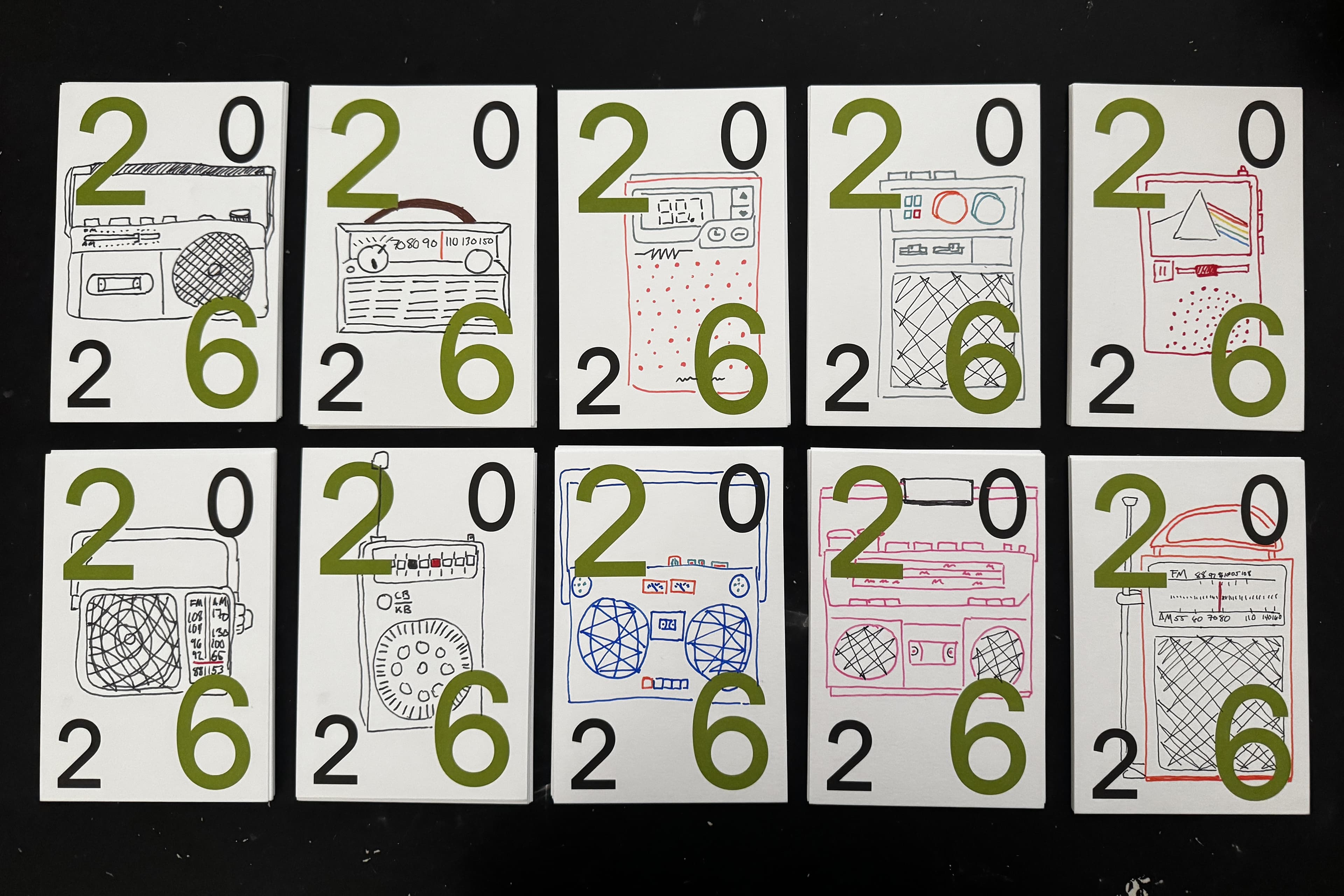 Ten white cards arranged in two rows on black, each printed with a large 2026 in green and black and hand-drawn in ink with a different radio, boombox or cassette player.