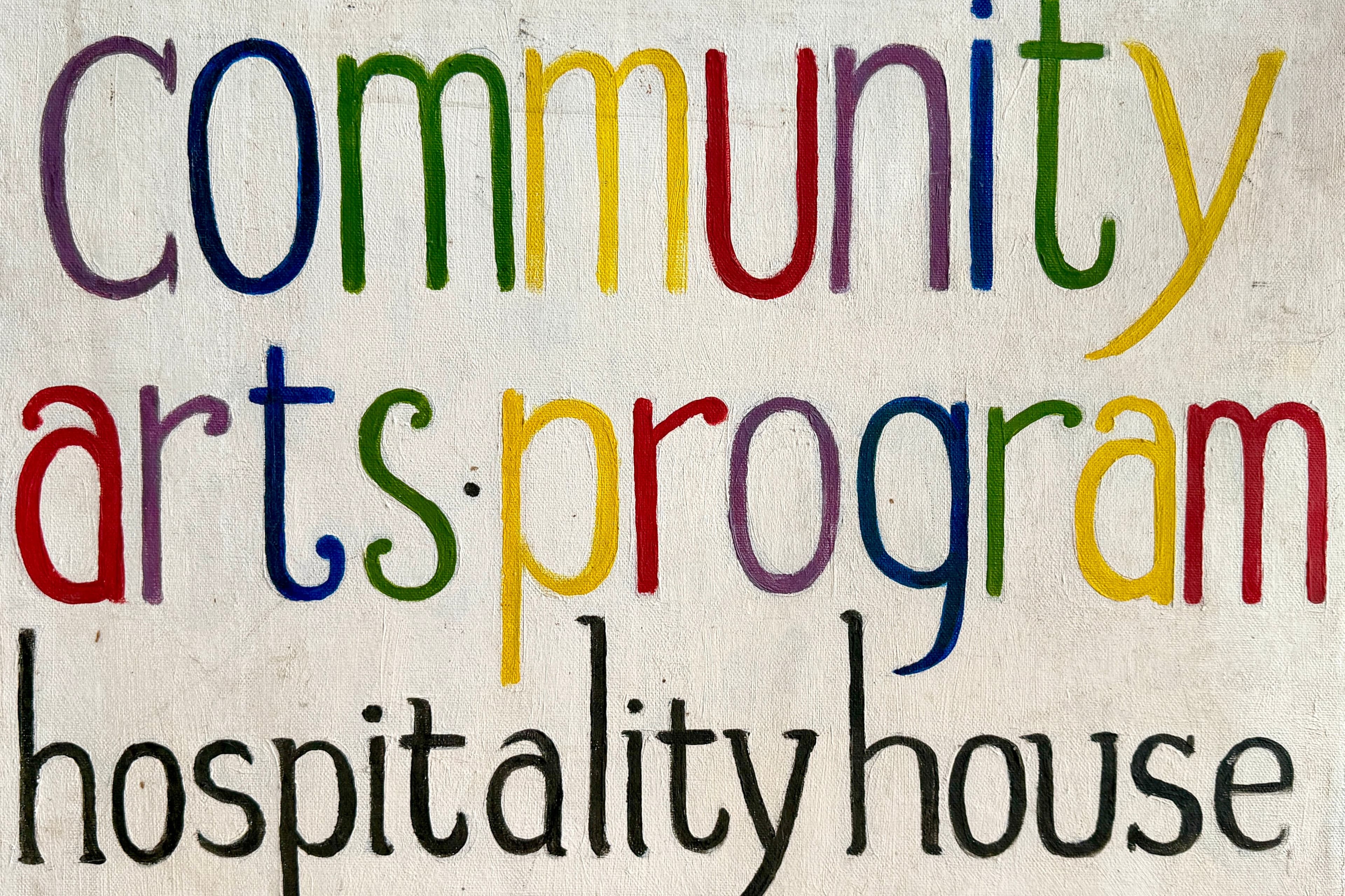 A hand painted text only sign that reads "community arts program" in rainbow colored lower case letters and "hospitality house" in black lower case letters.