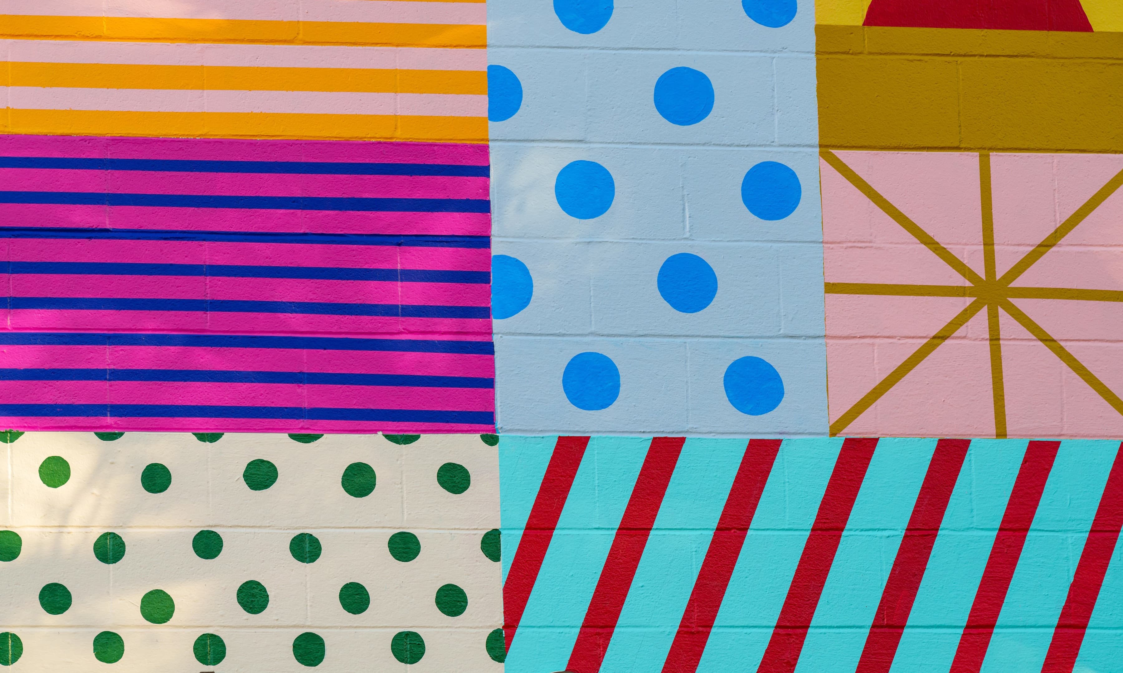 Detail of a mural project for the exterior of the San Luis Obispo Museum of Art. Rectangles and squares hold a single color field marked by differently colored polka dots; horizontal or diagonal stripes; or lines intersecting at a central point.