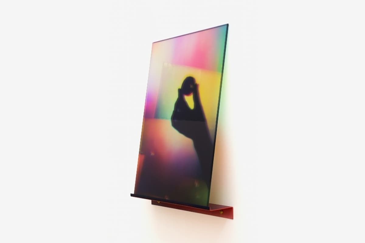 Colorful abstract photographic work showing the shadow of a hand holding a small sphere against a soft rainbow gradient background.