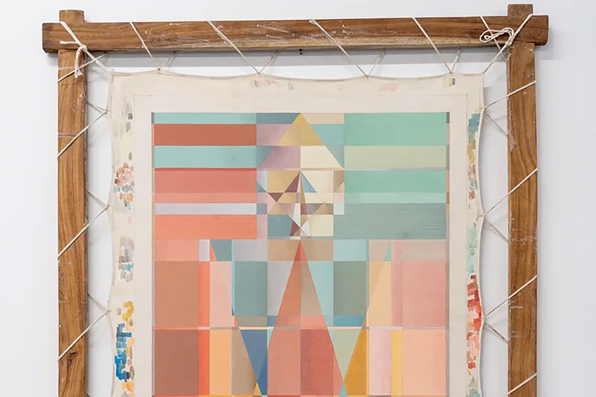 Abstract geometric painting in soft coral, teal, blue, yellow, and beige tones, featuring layered rectangles and triangular forms arranged in a symmetrical composition. The artwork is mounted on fabric within a rustic wooden frame, secured with white cord wrapped around the edges.