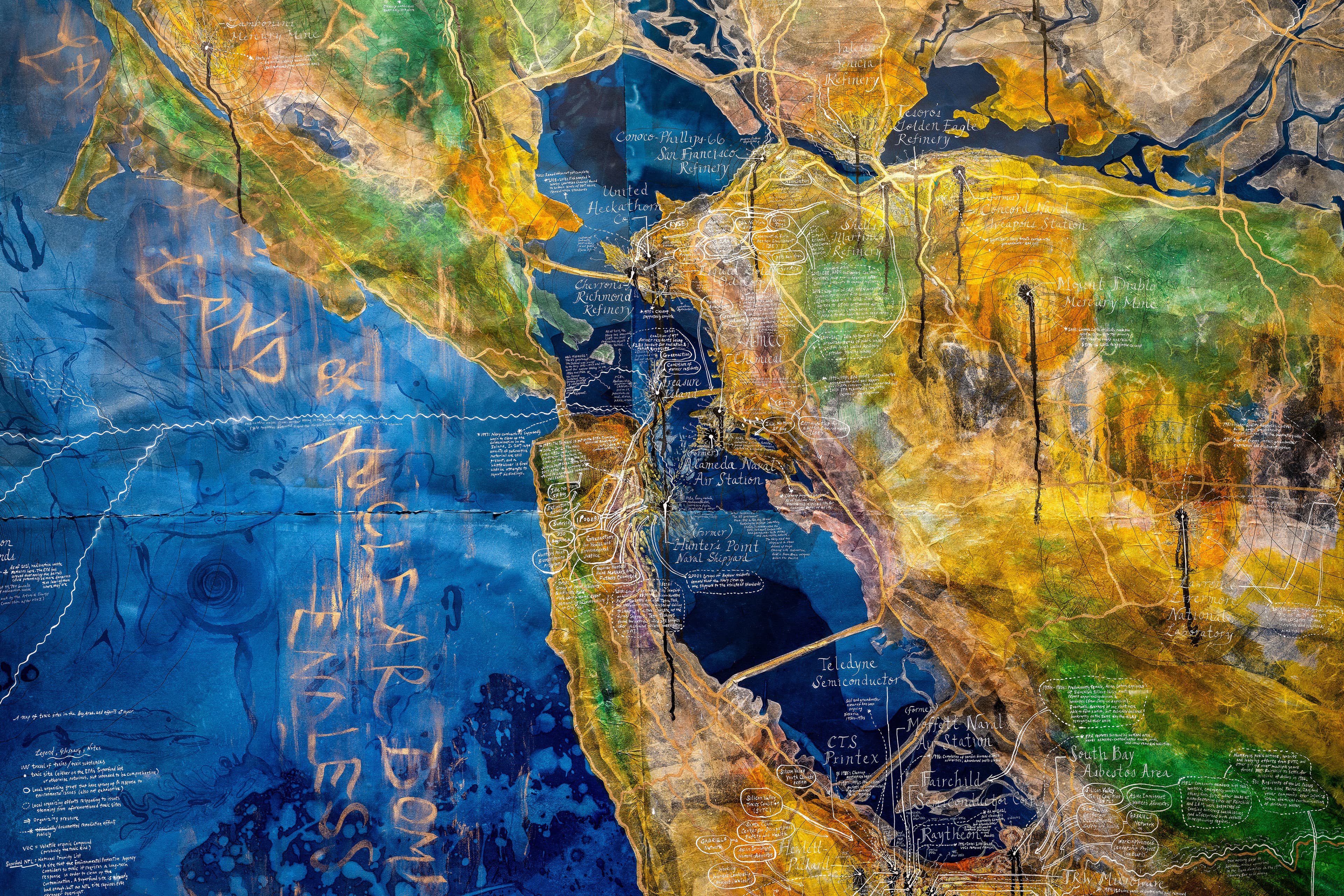 Close-up of a large mixed media collage map drawing with a deep Prussian blue cyanotype base, broken up by the texture of pools of liquid. The image is cropped to show a section of the map that depicts the San Francisco Bay area, collaged onto the cyanotype with numerous layers of semi-translucent paper dyed in a gradient of rainbow colors. Annotations of white text fill spread across the image in cartoon text bubbles, arrows and other diagrammatic iconography.
