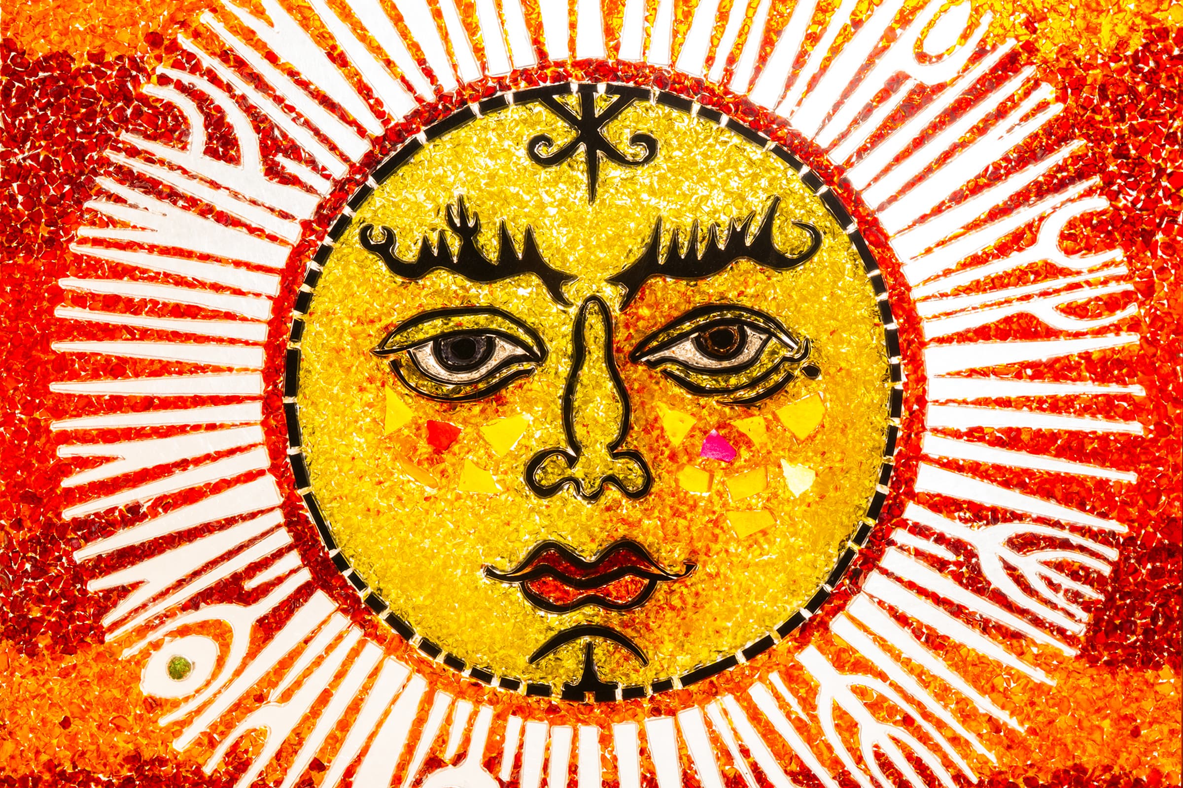 A painting depicting a sun face. The face is rendered in a bright yellow with prominent black outlines defining its expressive eyes, nose, lips, and elaborate wavy eyebrows. Surrounding the circular yellow face is a dense corona of elongated, radiating orange and red mosaic elements that mimic sunbeams, all set against a white background.