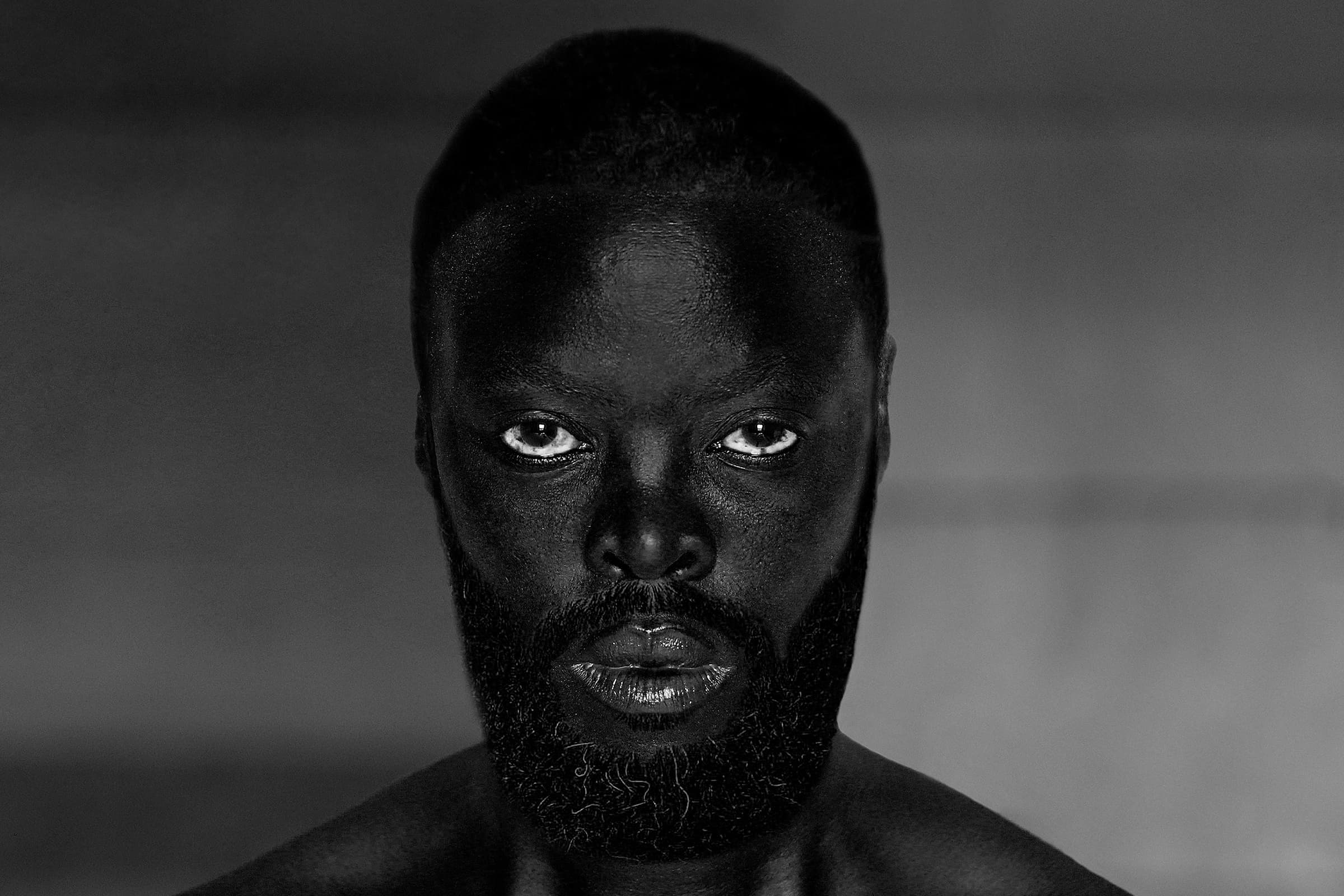 Self portrait of photographer Zanele Muholi with a full beard and hair pulled back.